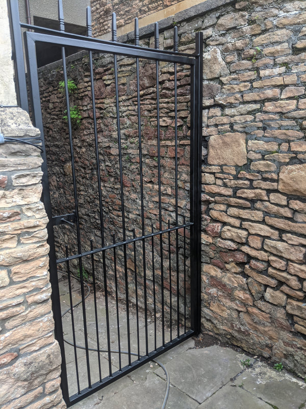 Side access wrought iron metal gate with a hand-painted finish